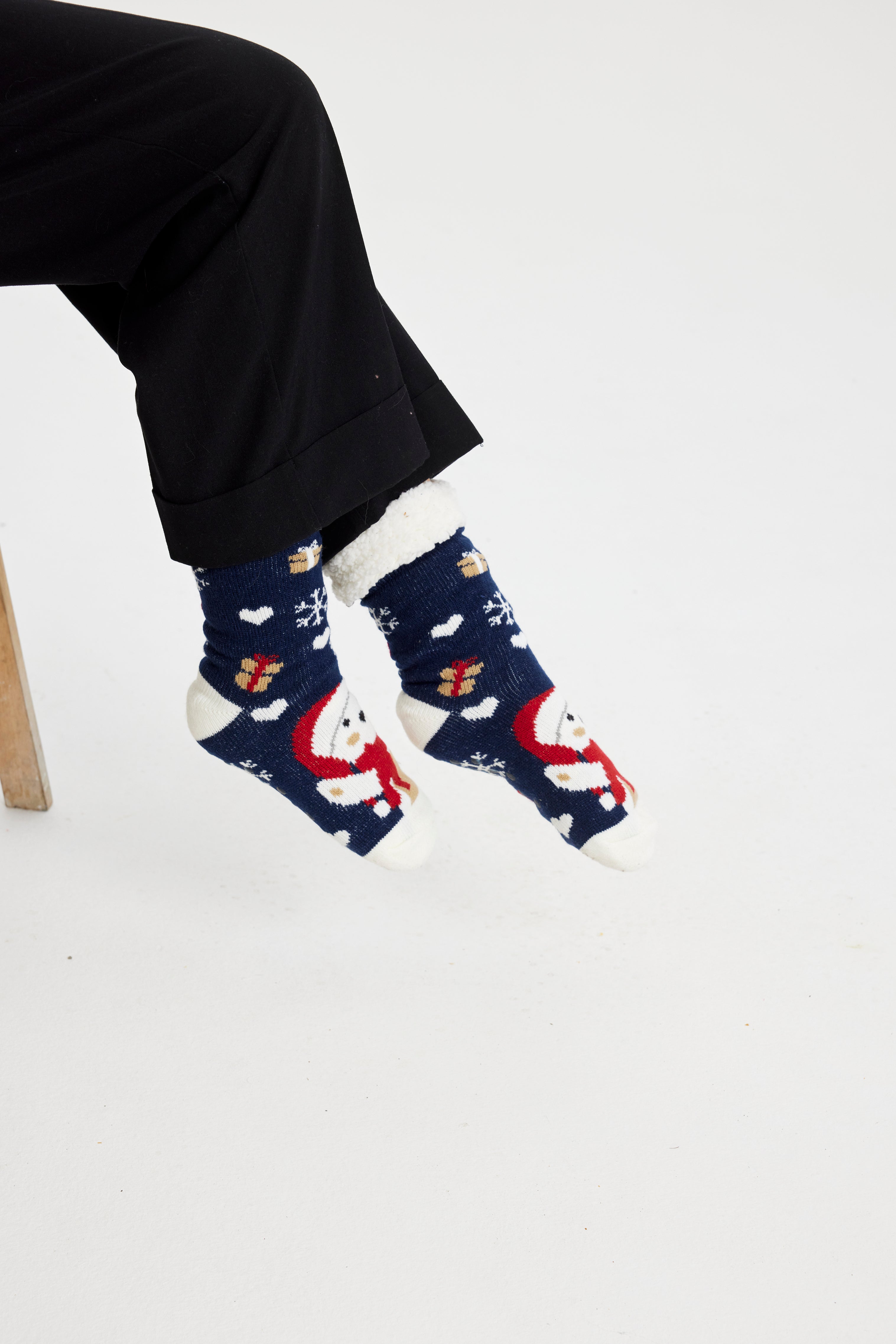 Ett par fötter i blå julstrumpor med jultomten och julklappar på.